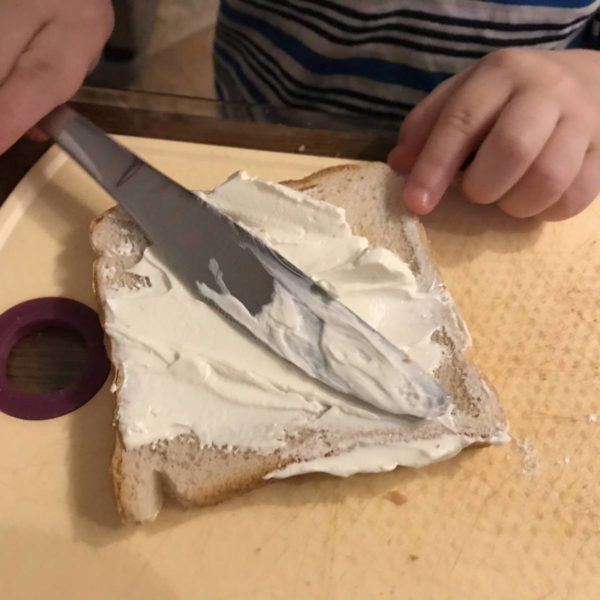 Kind schmiert sich sein Brot