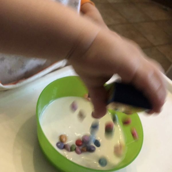 Kind macht Joghurt mit Schokolinsen